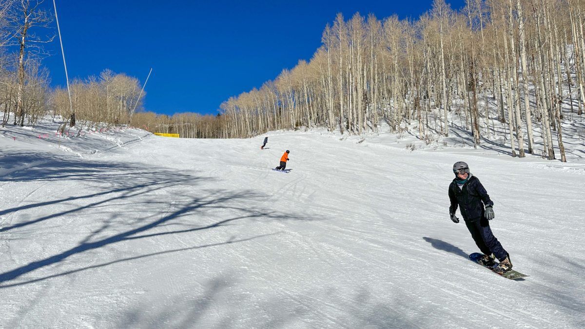 Snowboarders in a race on the side of the town of Canyons of Park City Mountain.