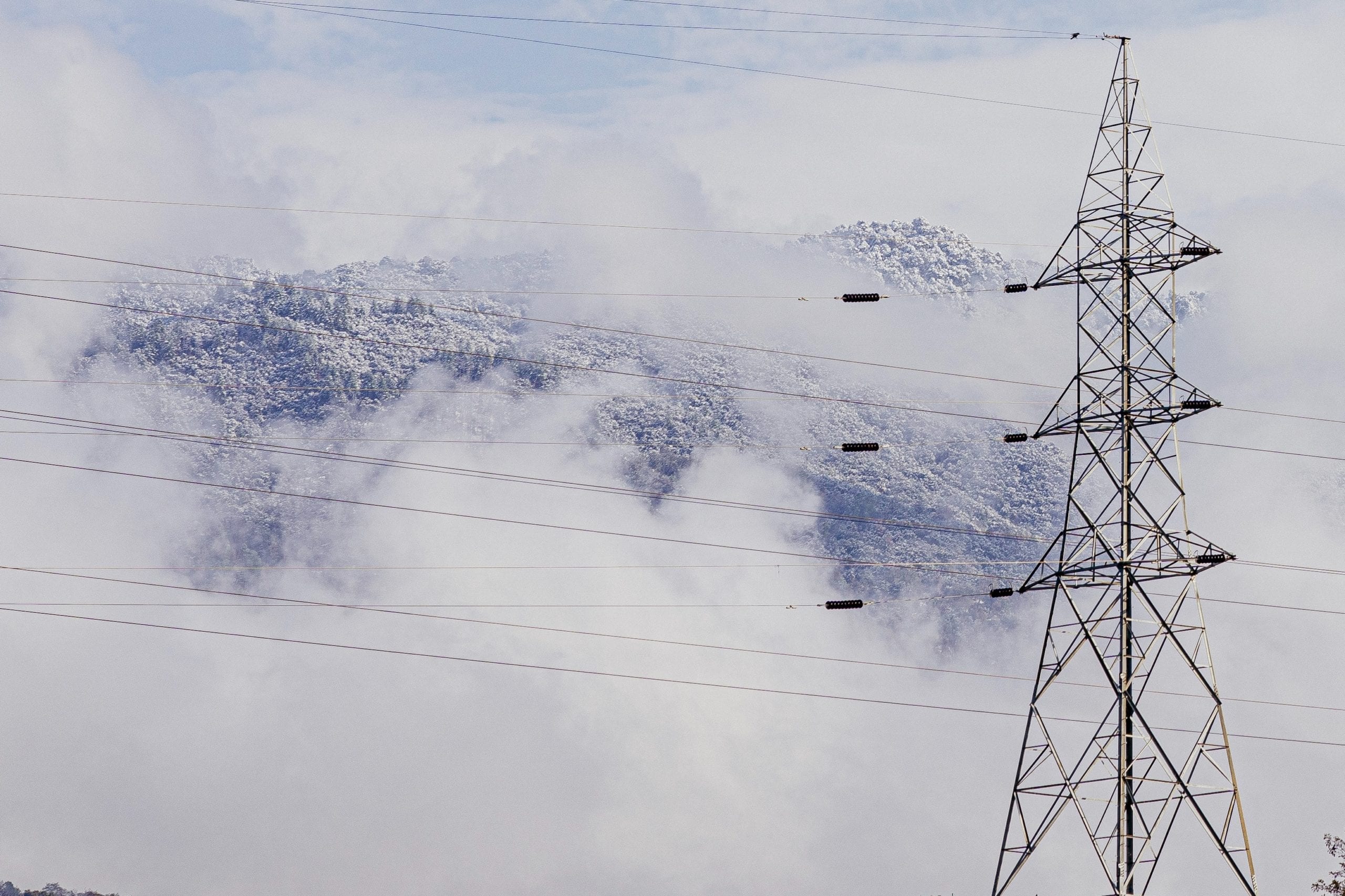 gray transmission tower near mountain during daytime