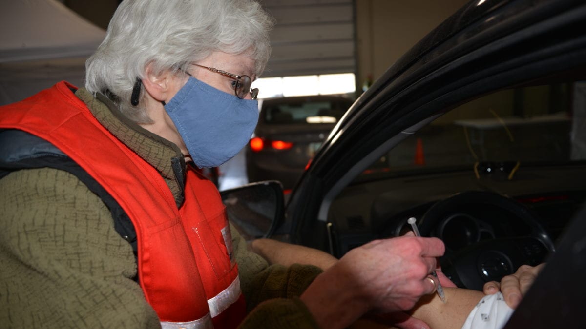 A vaccination clinic worker vaccinating a Summit County resident in their car.
