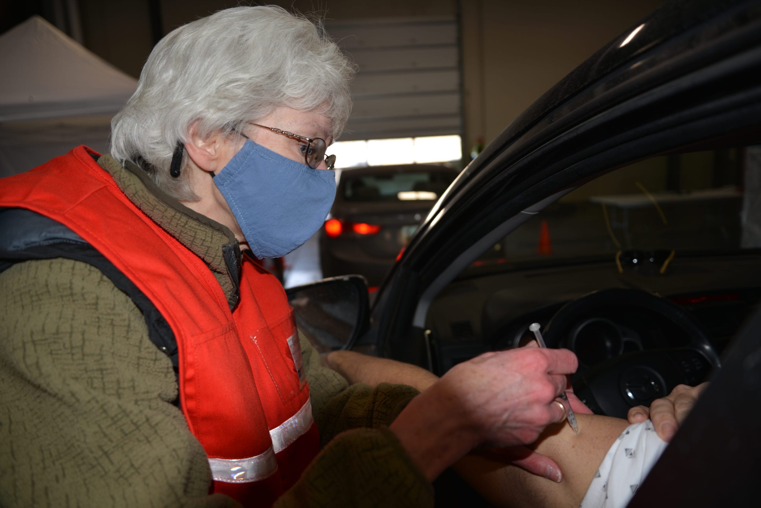 A vaccination clinic worker vaccinating a Summit County resident in their car.