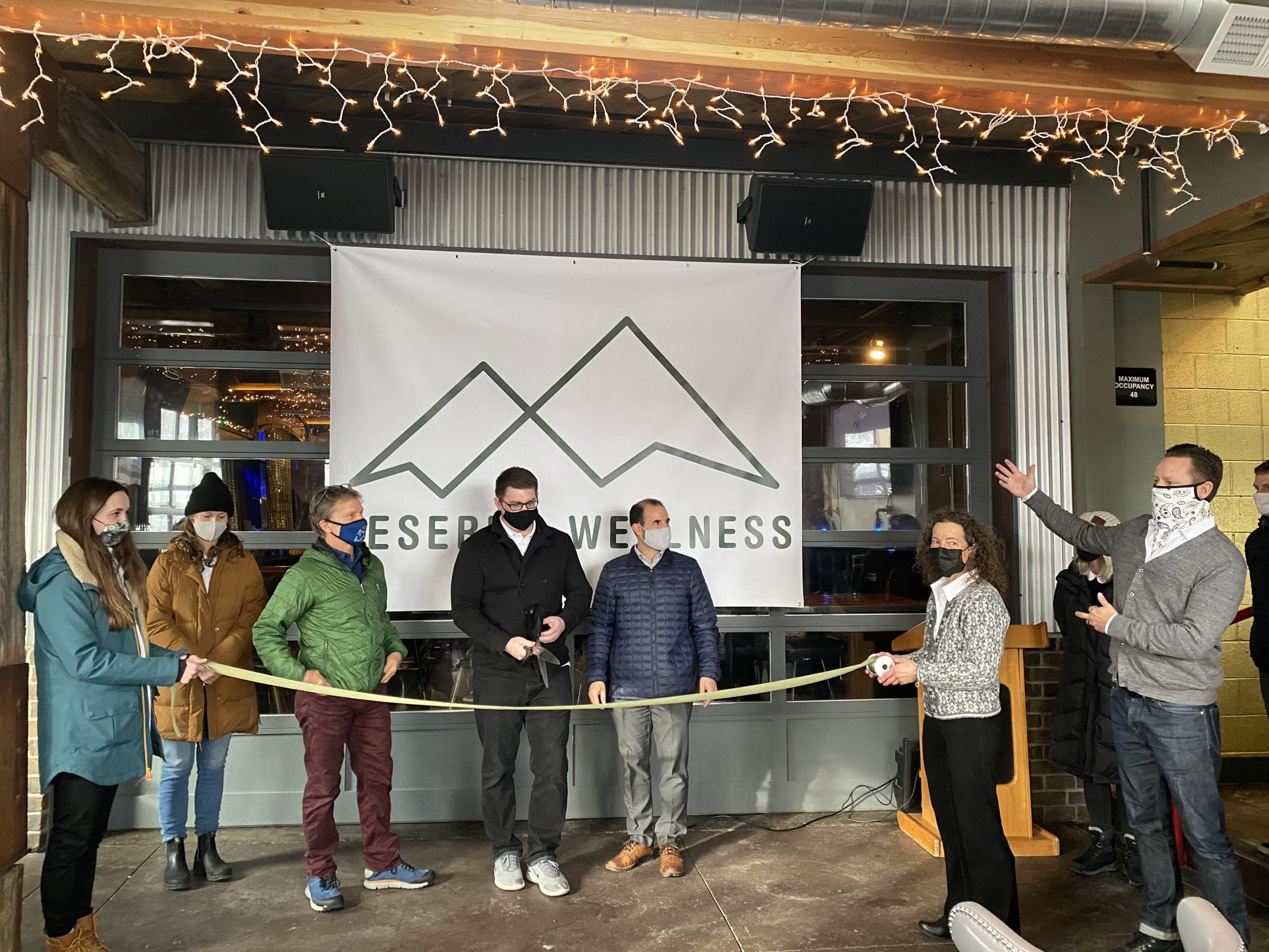 Pharmacy Manager Brian Woods prepares to ribbon-cut to celebrate Deseret Wellness's new cannabis dispensary. He's joined by Park City Councilman Tim Henney (green jacket), Utah Dept. of Health Center for Medical Cannabis Director Rich Oborn (blue jacket) and Market President Jeremy Sumerix at far right.