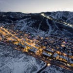 Night falls over Park City, Utah, where two mountain icons share the skyline and starkly different reputations.