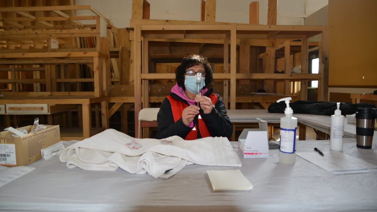 A vaccination clinic worker prepares the Moderna vaccine for use.
