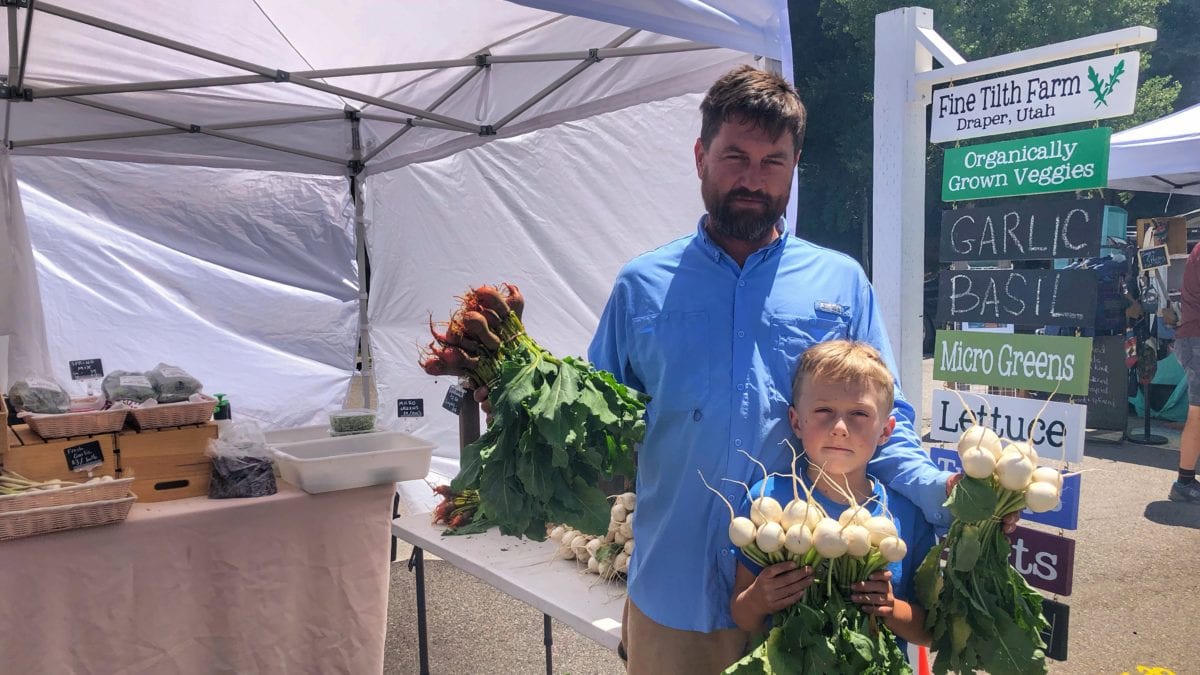 Joaquim Hailer and son Atticus hold bouquets of root veggies.