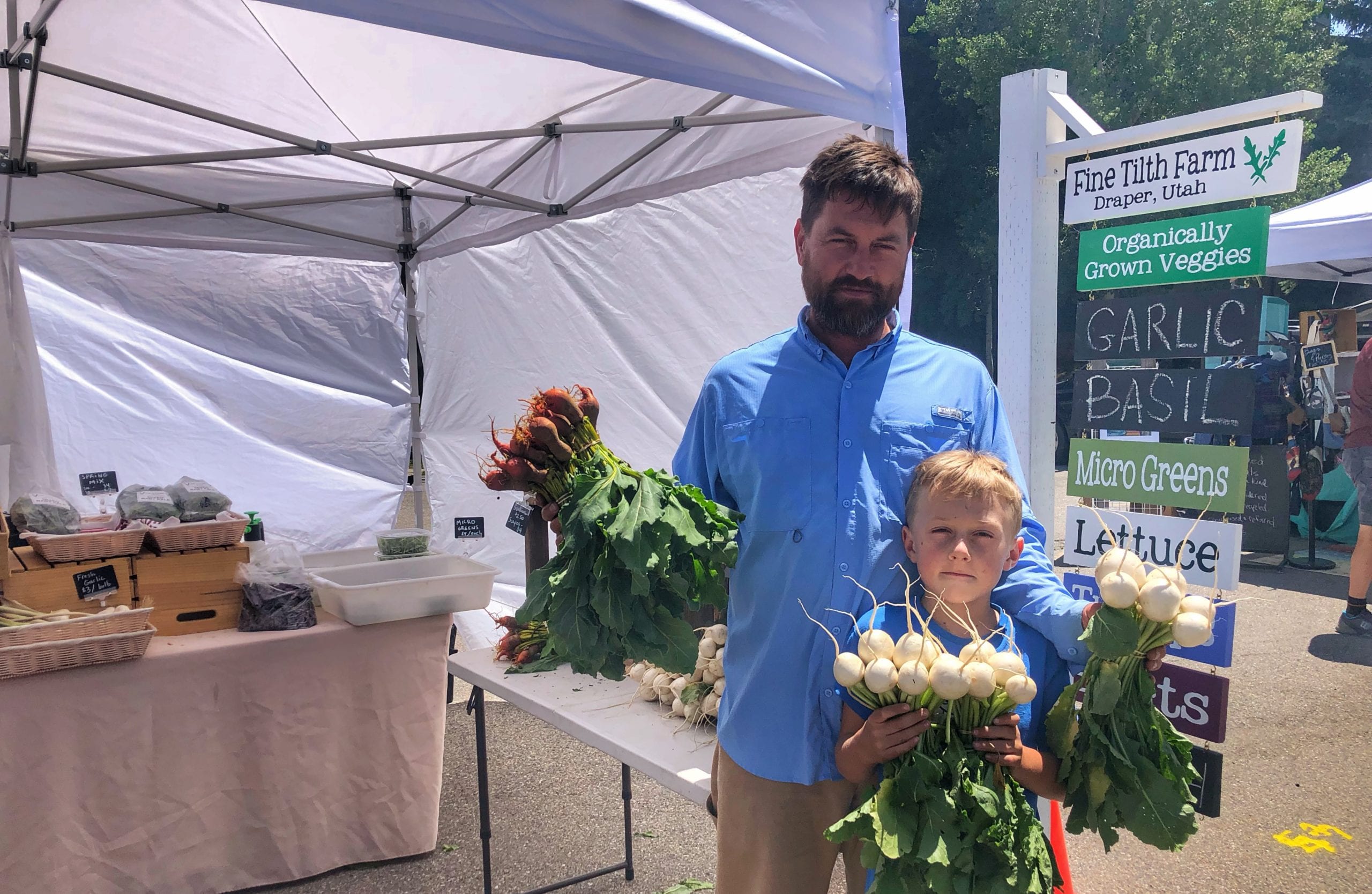 Joaquim Hailer and son Atticus hold bouquets of root veggies.