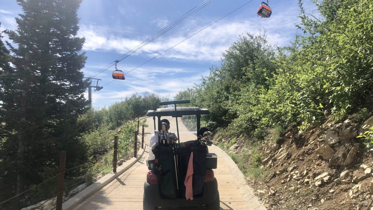 Golf cart driving under the orange bubble chair at Park City Mountain, Canyons Village.