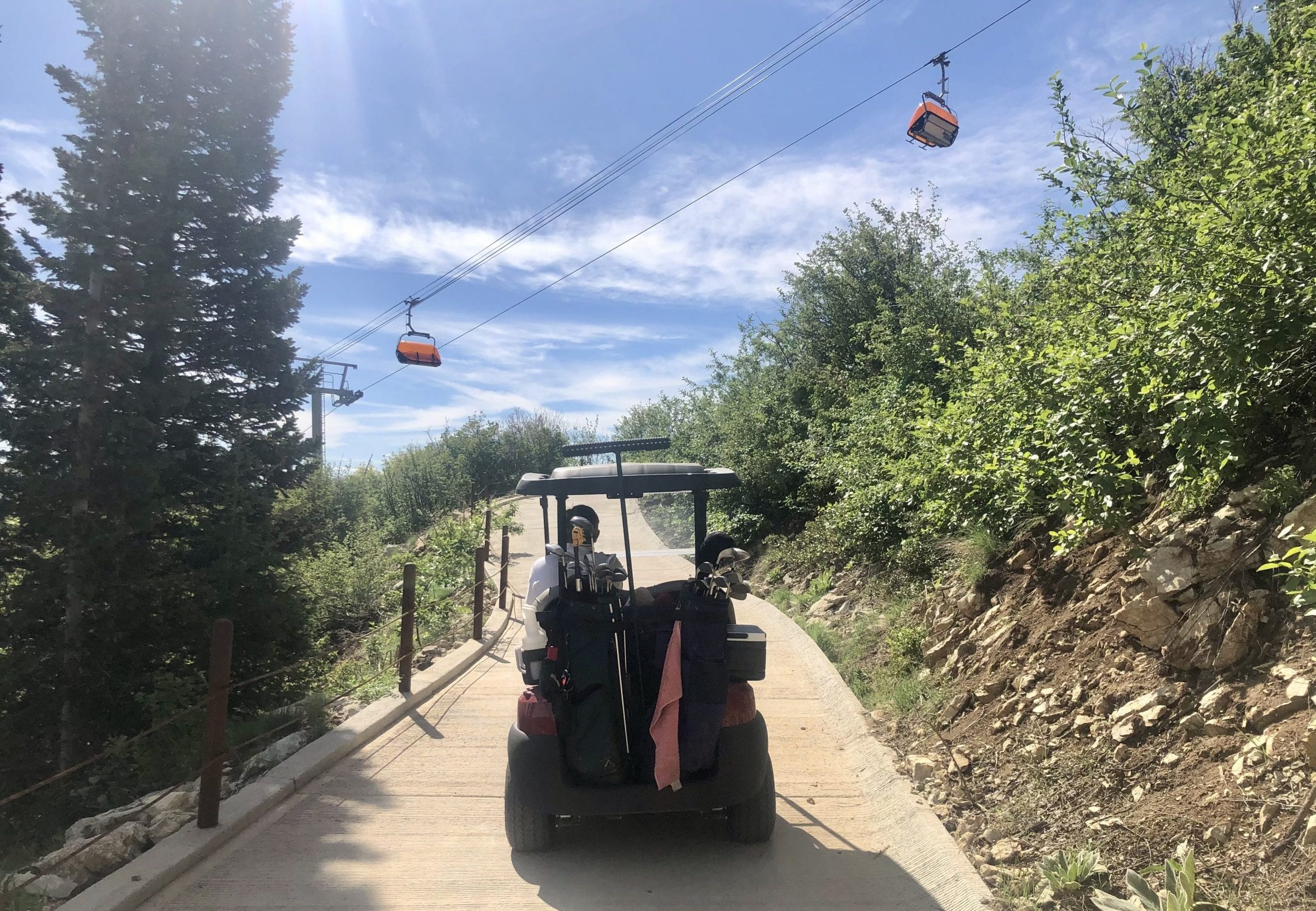 Golf cart driving under the orange bubble chair at Park City Mountain, Canyons Village.