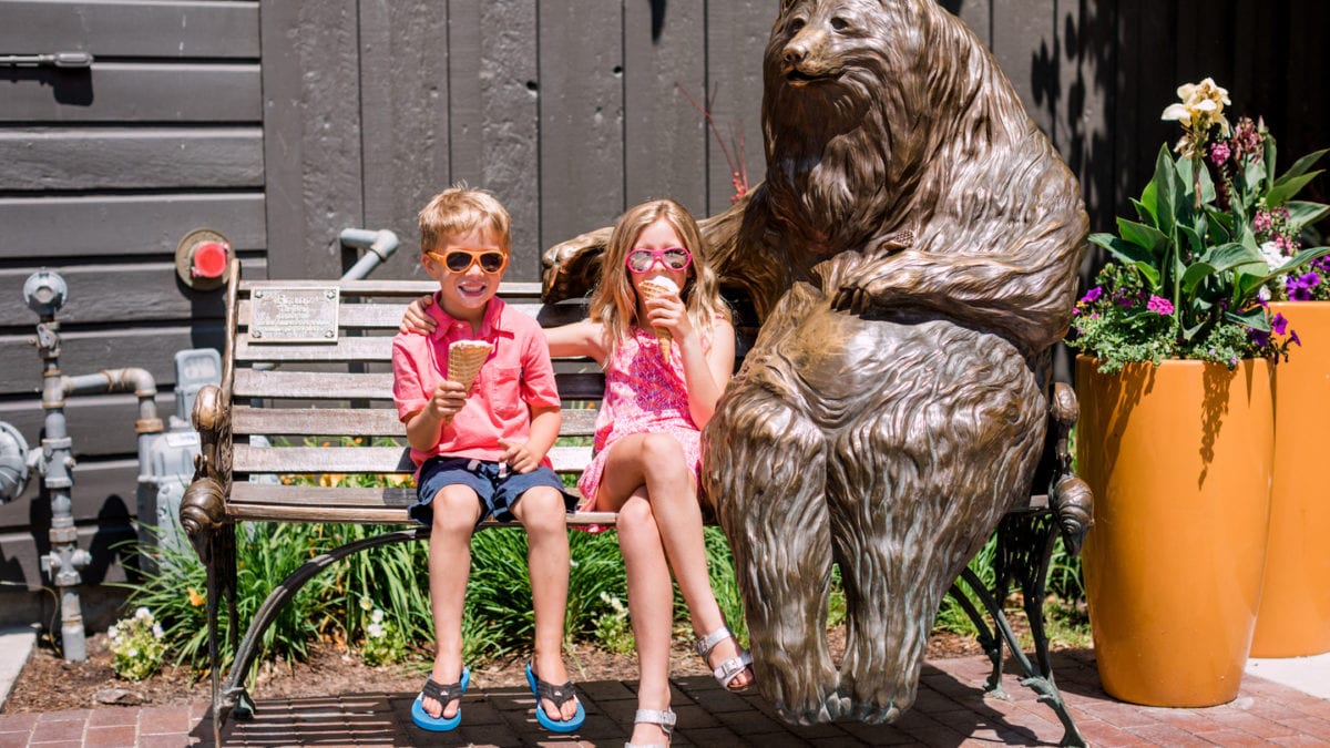 Kids eating ice cream on bench with Franz, an iconic bear sculpture on Main Street in Park City.