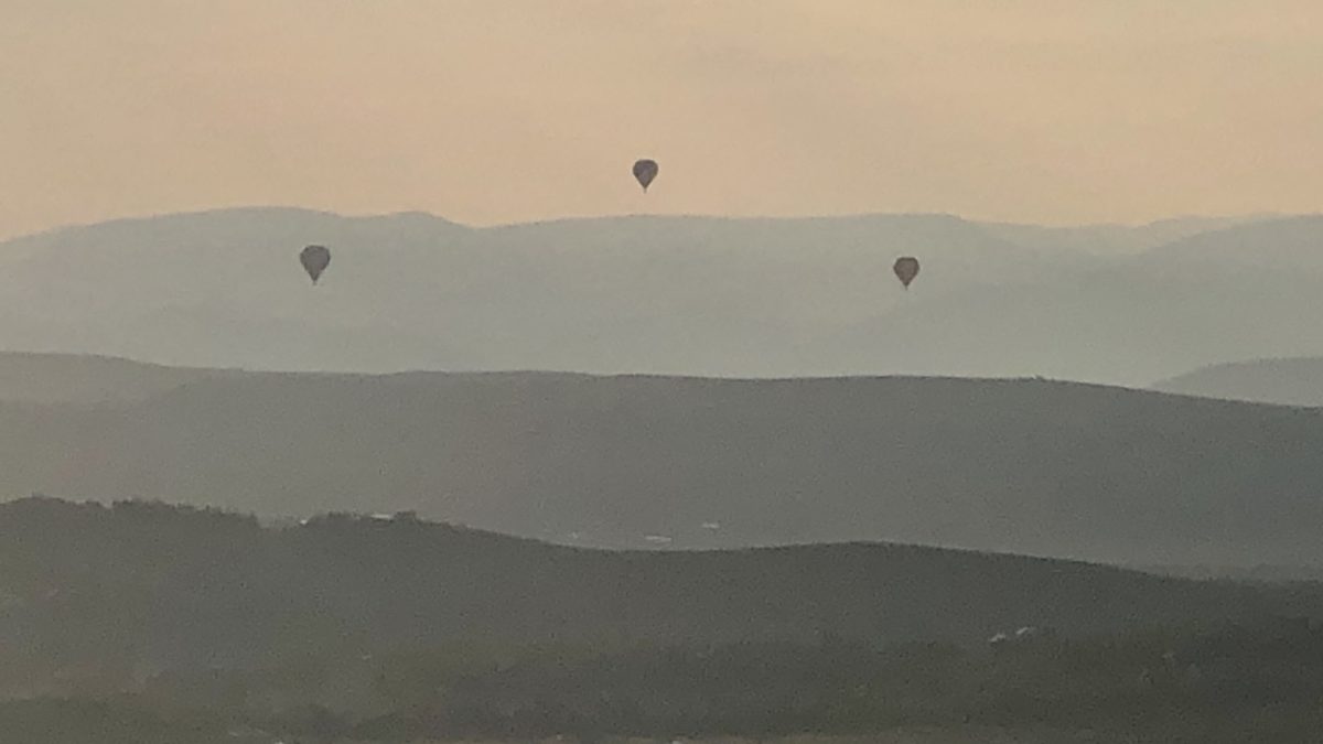 Three hot air balloons over three mountains.