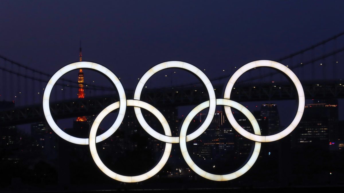 Tokyo 2020 Olympic rings with Rainbow Bridge and the Tokyo Tower in the background.