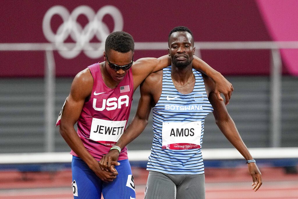 Isaiah Jewett, of the USA, and Nijel Amos, right, of Botswana, shake hands and cross the finish line together after falling together and helping each other up in the 800-meter semifinal at the 2020 Summer Olympics, Sunday, in Tokyo.