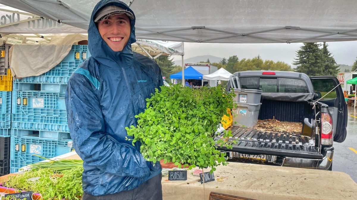 Madison Goodman of Madsnacks Produce shows off his sprouts during a down pour.