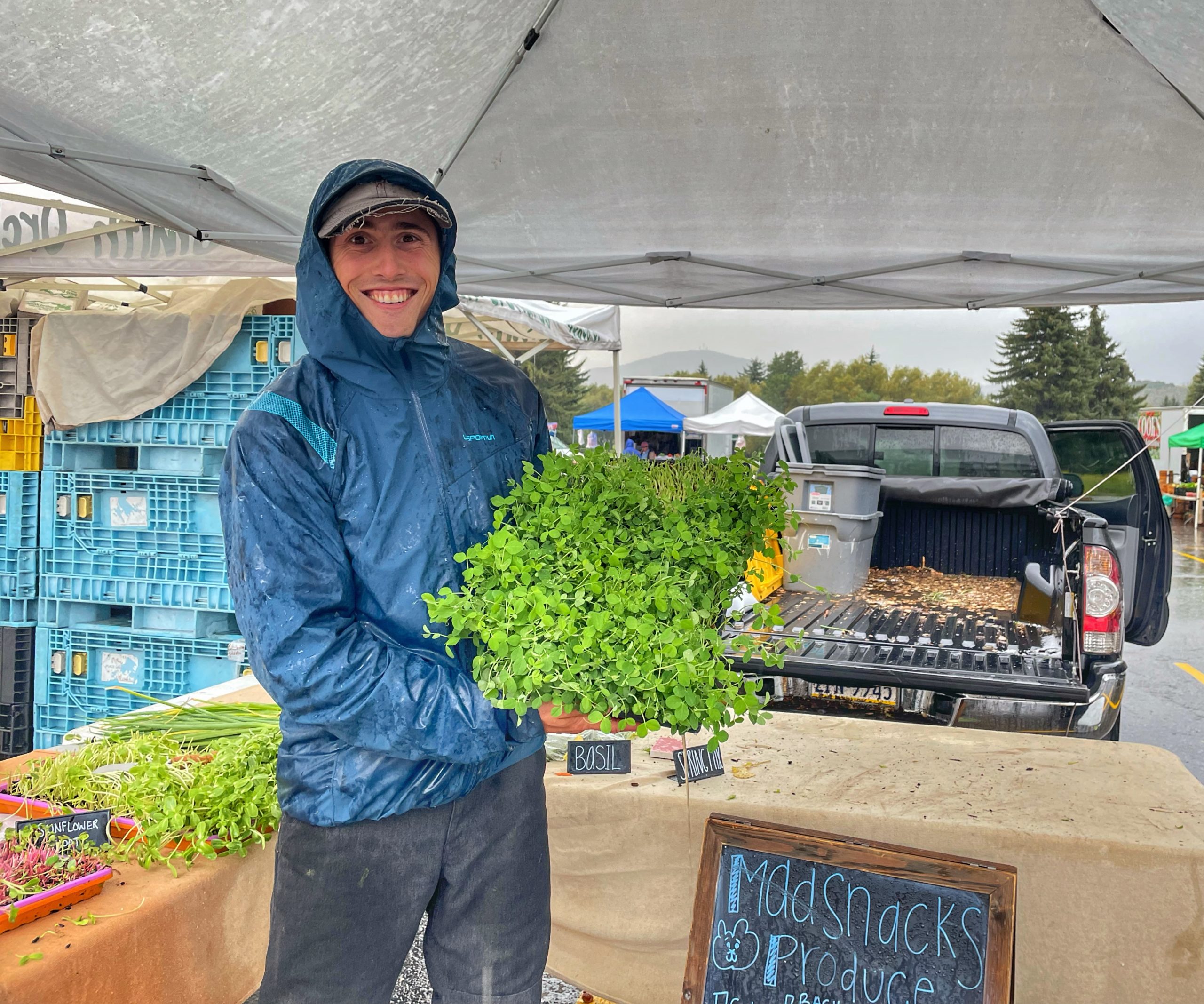 Madison Goodman of Madsnacks Produce shows off his sprouts during a down pour.