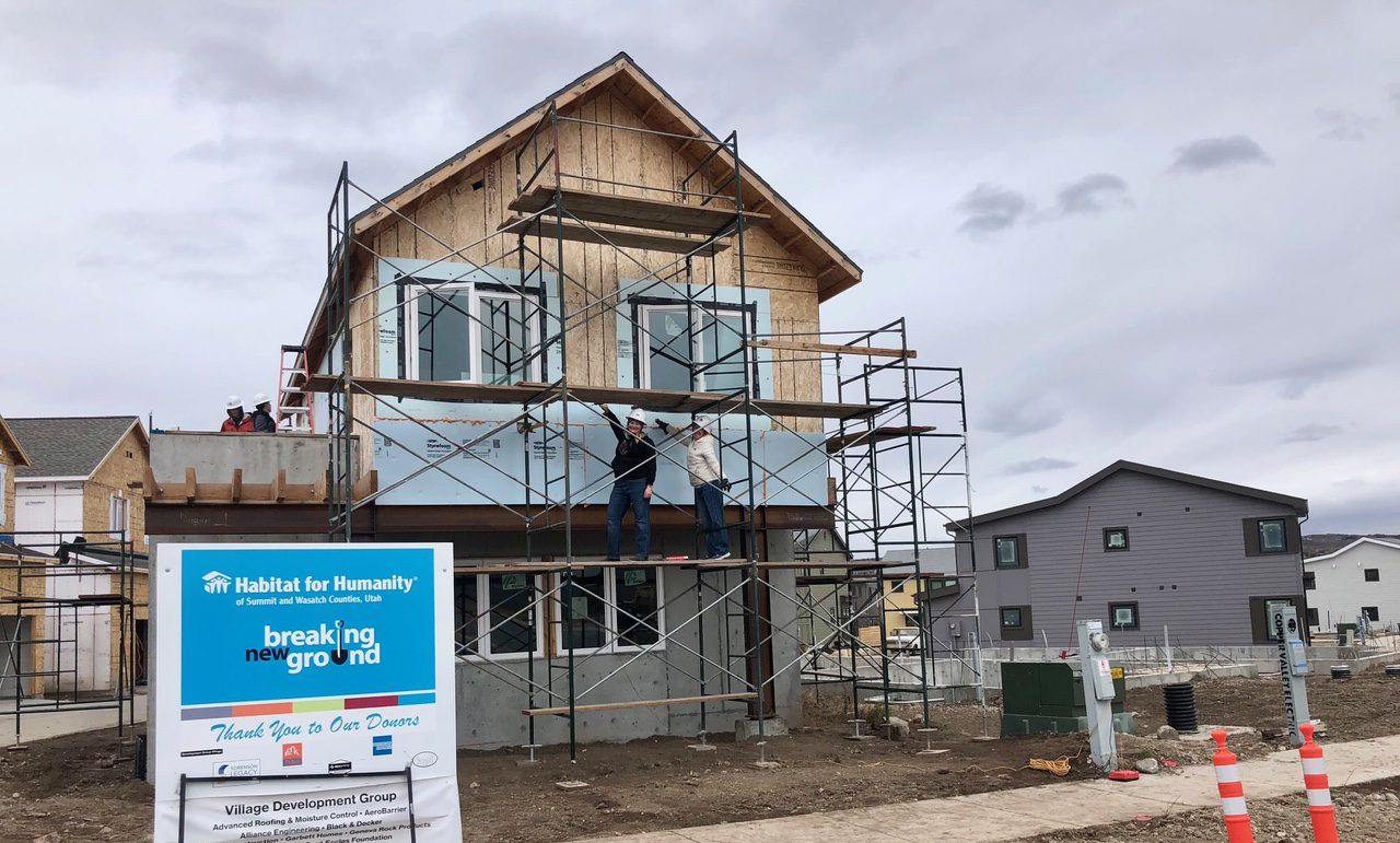 Habitat For Humanity's newest home in Park City with homeowner Chelsea Jones (L) and volunteer Casey Lebwohl (R) on the scaffolding.