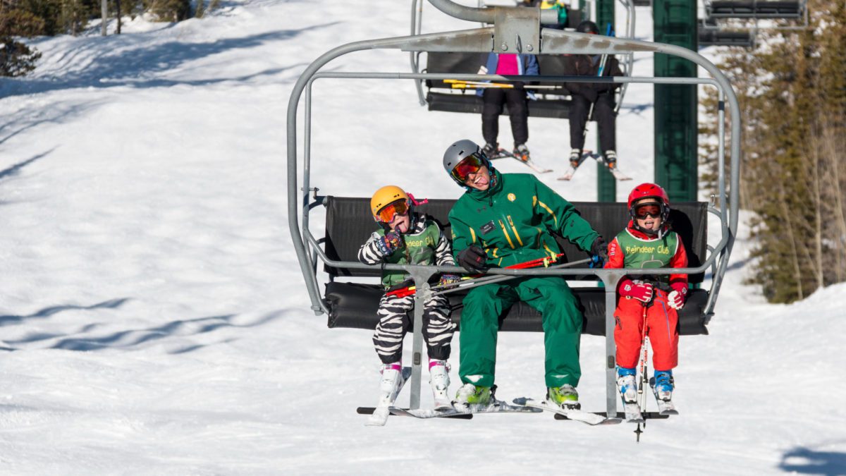 An instructor on a ski lift with two kids.