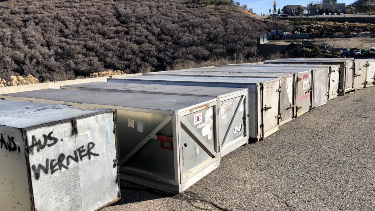 Bobsled international travel crates sit on the sidelines at the Utah Olympic Park while their contents race down the track.