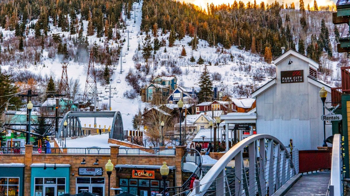 white wooden bridge over snow covered mountains during daytime