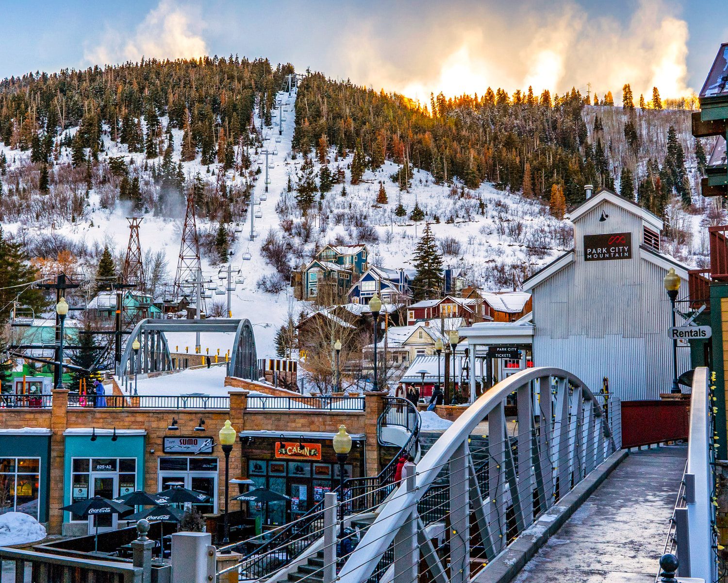 white wooden bridge over snow covered mountain during daytime