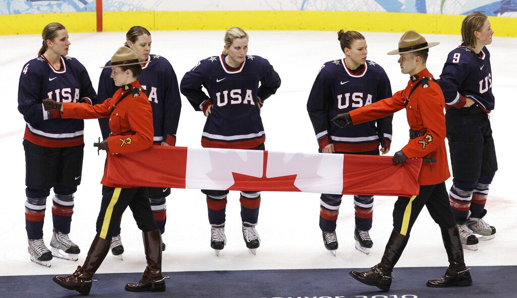 USA players watch as the Canadian flag is carried during the medal ceremony after Canada beat USA 2-0 to win the women's gold medal ice hockey game at the Vancouver 2010 Olympics in Vancouver, British Columbia, Thursday, Feb. 25, 2010.