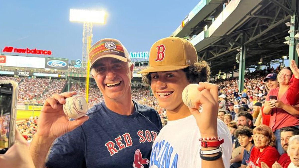 Father and son at Fenway Park both catch baseballs at Red Sox Yankees game.