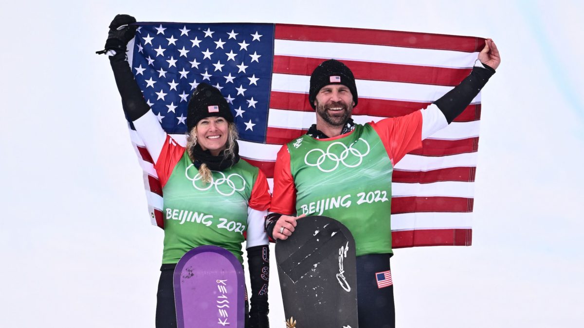 Gold medallists USA's Lindsey Jacobellis and USA's Nick Baumgartner hold their national flag on the podium during the venue ceremony after the snowboard mixed team cross final during the Beijing 2022 Winter Olympic Games at the Genting Snow Park Stadium in Zhangjiakou on February 12, 2022.