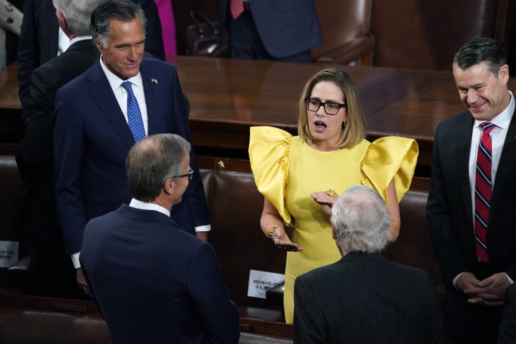 Sen. Kyrsten Sinema, Ind-Ariz., center, speaks with Sen. Mitt Romney, R-Utah, left, and Sen. Todd Young, R-Ind., right, and others, before President Joe Biden arrives to deliver his State of the Union speech to a joint session of Congress, at the Capitol in Washington, Tuesday, Feb. 7, 2023.