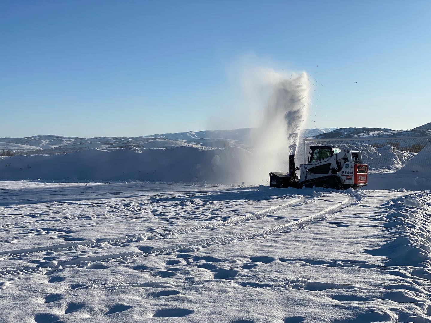 A bobcat with a snowblower front end working to clear snow