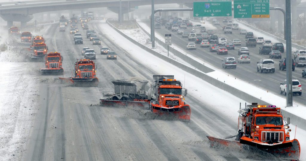 A series of snow plows working together to clear I-80.