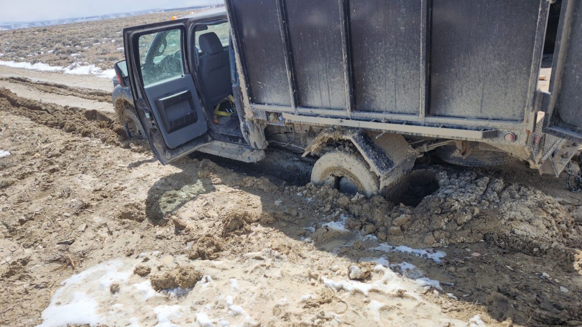 A truck buried to the frame in mud.