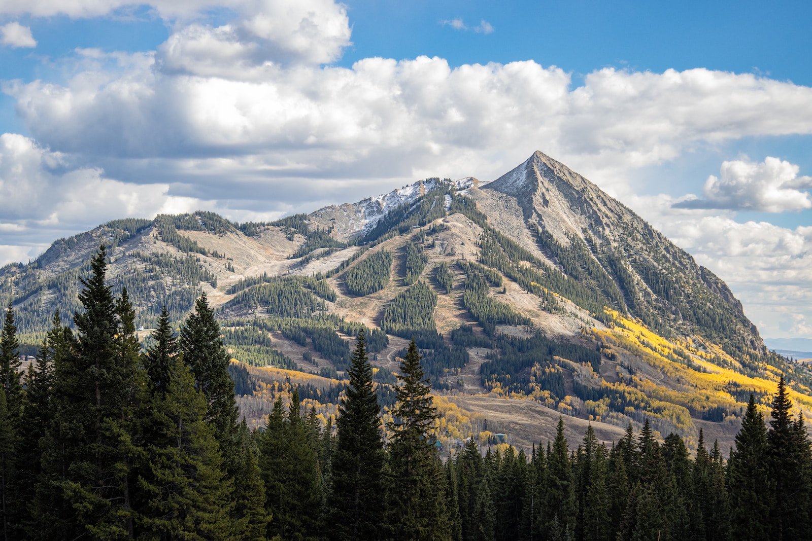 A mountain with trees and clouds.