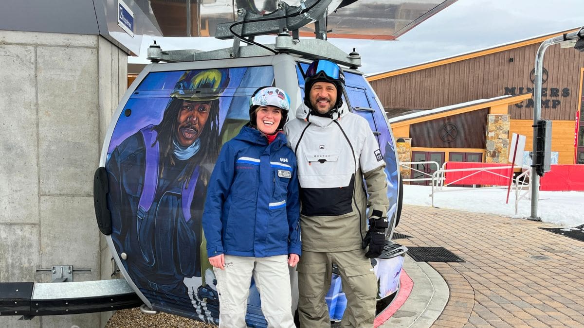Deirdra Walsh and Lamont Joseph White pose in front of his artwork on the Quicksilver Gondola, which had its winter unveiling December 20, 2023.