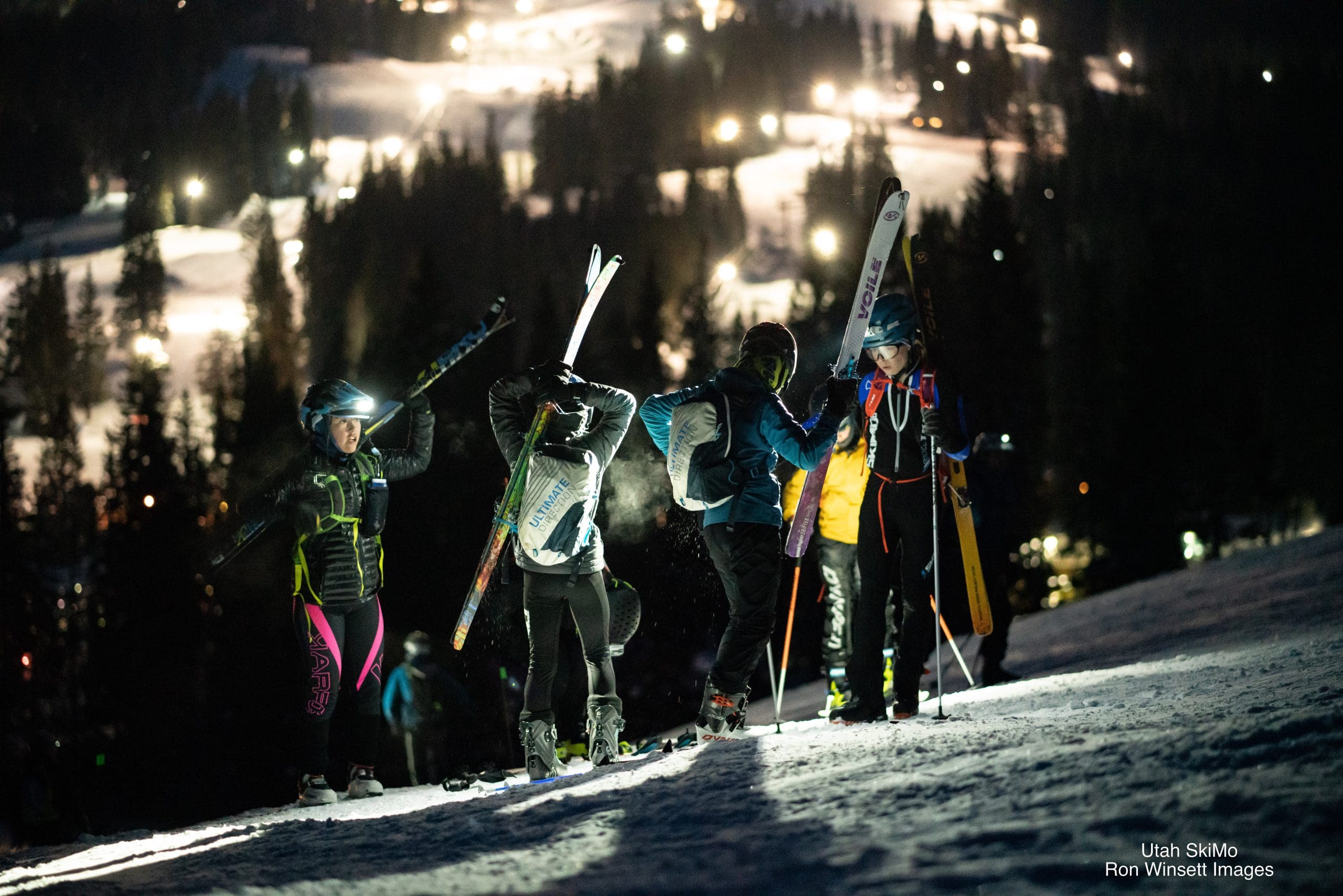 Youth athletes quickly attach their skis to their packs to make their way up a booter.