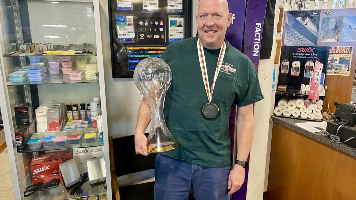 Wax tech Andy Buckley at Rennstall holding a Crystal Globe infront of his five Olympics credentials.