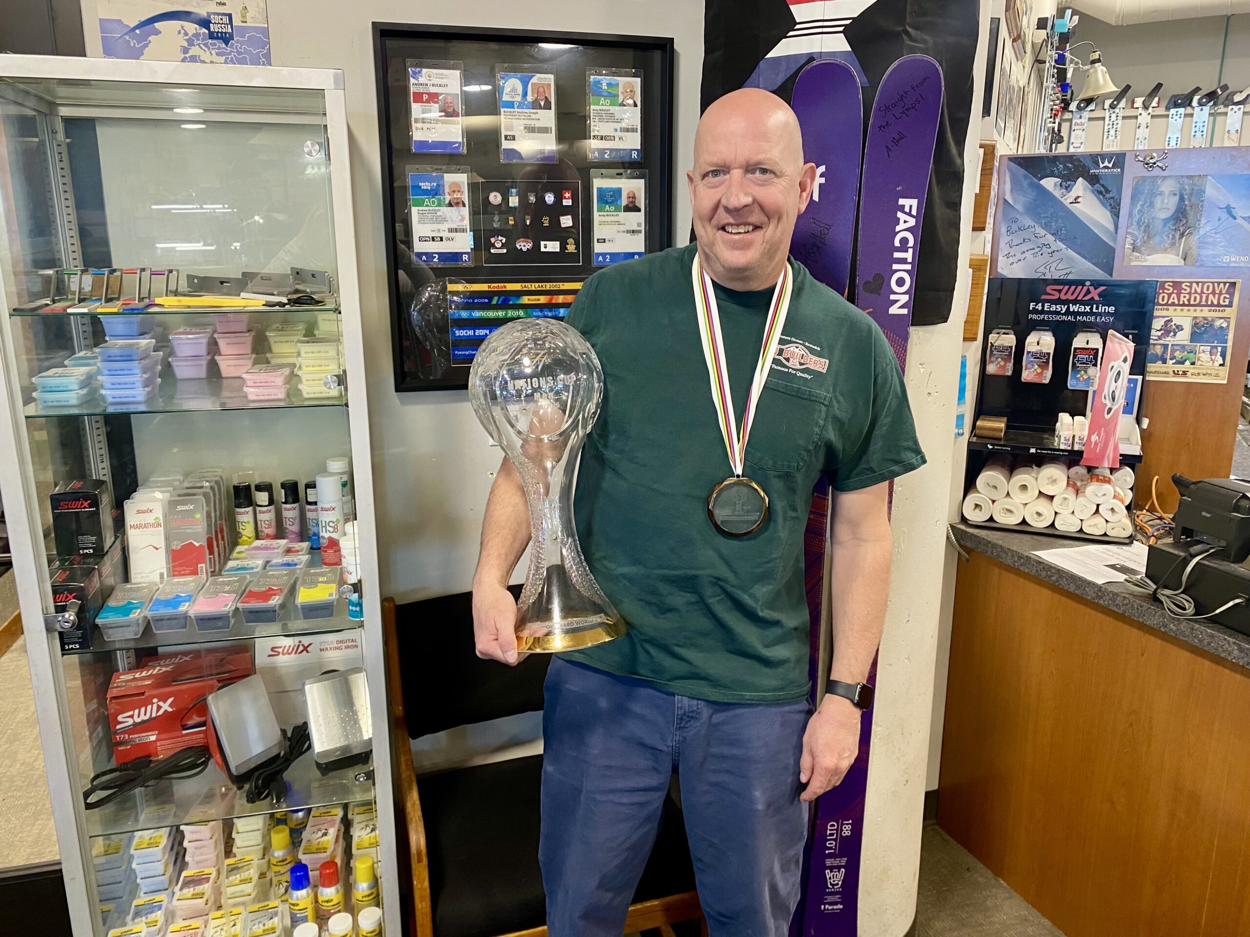 Wax tech Andy Buckley at Rennstall holding a Crystal Globe infront of his five Olympics credentials.