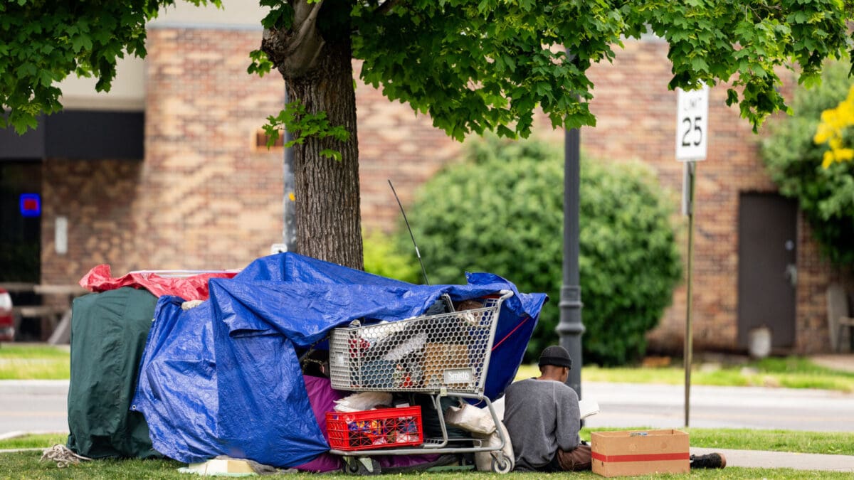 A person experiencing homelessness sits on the side of a street in Salt Lake City on Saturday, May 25, 2024.