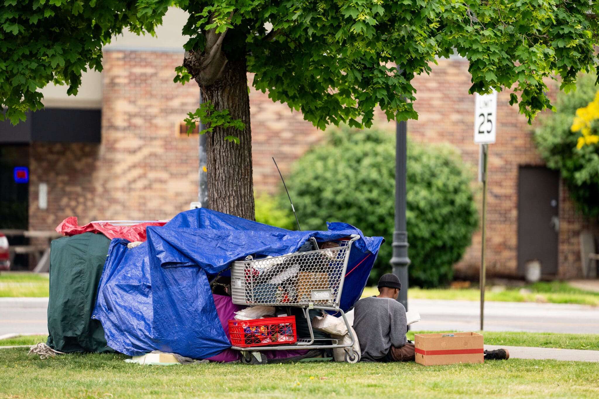 A person experiencing homelessness sits on the side of a street in Salt Lake City on Saturday, May 25, 2024.