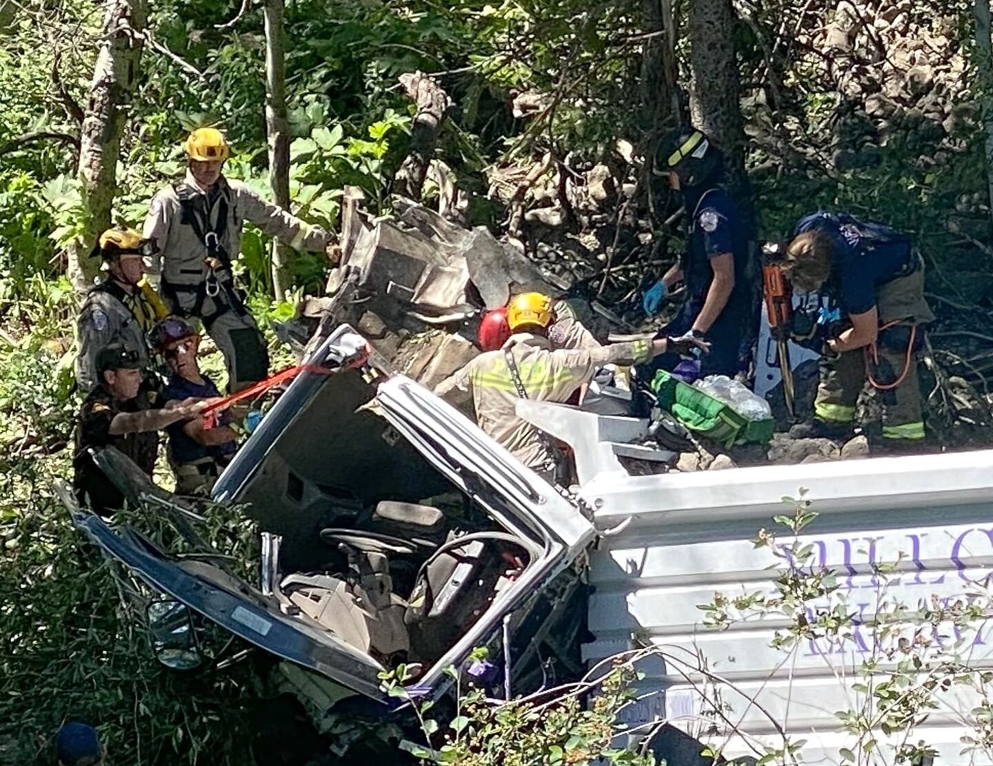 Rescue crews work to extricate the driver after a dump truck plummeted 200 feet into a ravine in Tollgate Canyon.