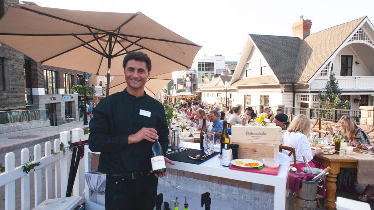 Courchevel's bartender shows a wine offering as the sun sets at Savor the Summit 2024 on Main Street in Park City.