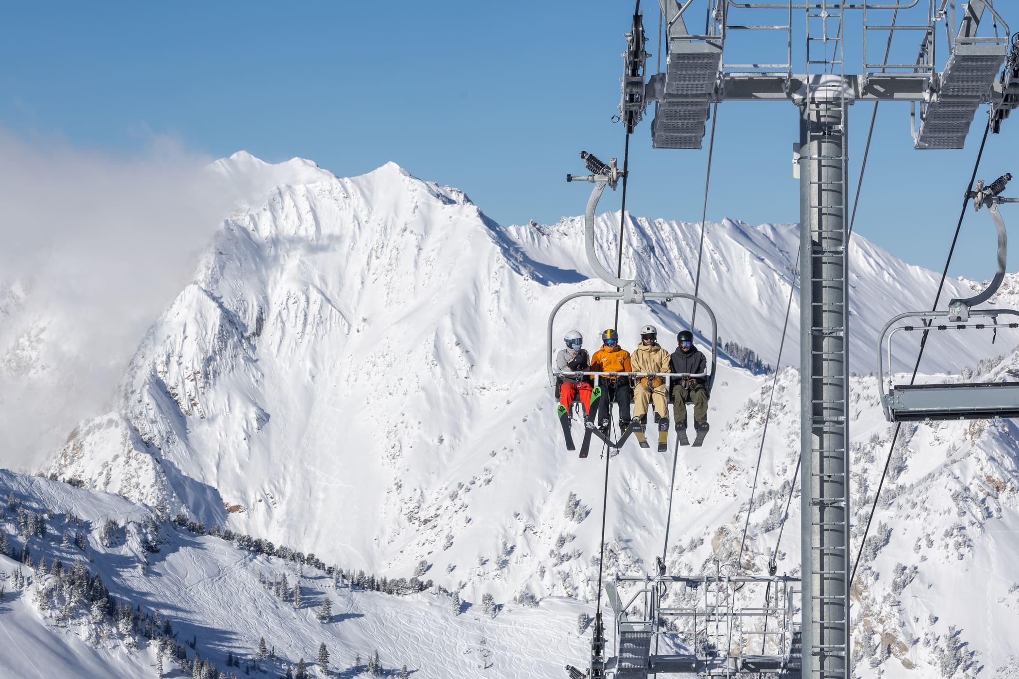 skiers ride up the Supreme lift at Alta on a sunny powder day.