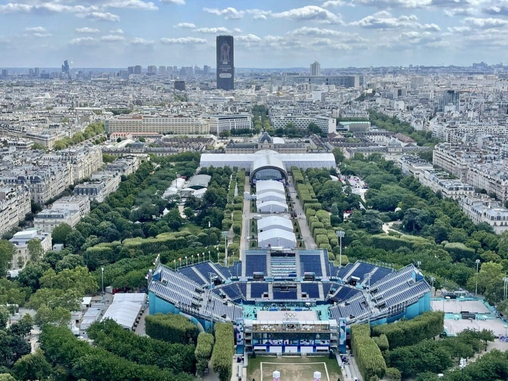 In Paris at the 2024 Olympics with the tall, black, rectangular Montparnasse Skyscraper in the background wrapped in the image of a runner like BYU's Keneth Rooks who won the Steeplechase Silver for the USA.