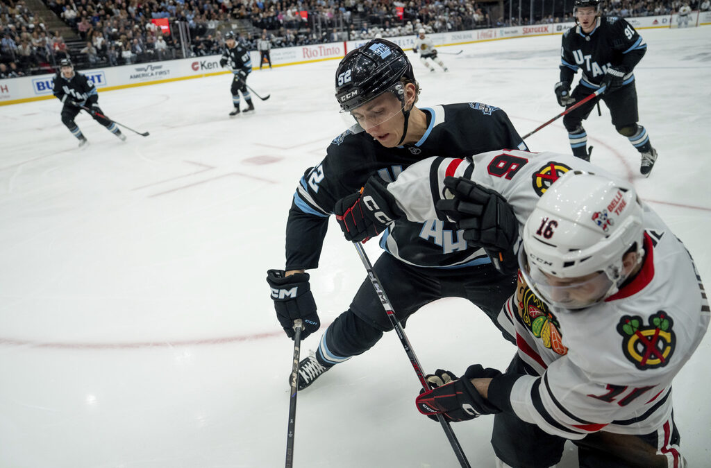 Utah Hockey Club defenseman Vladislav Kolyachonok (52) puts Chicago Blackhawks center Jason Dickinson (16) into the boards during the first period of an NHL hockey game, Tuesday, Oct. 8, 2024, in Salt Lake City. (AP Photo/Spenser Heaps)