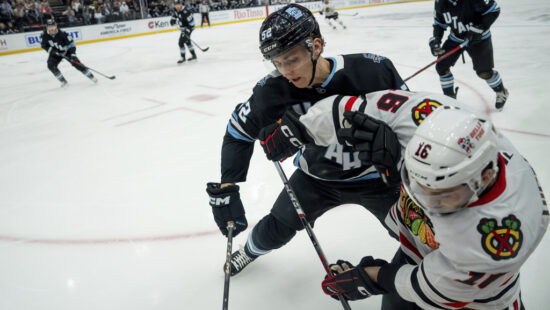 Utah Hockey Club defenseman Vladislav Kolyachonok (52) puts Chicago Blackhawks center Jason Dickinson (16) into the boards during the first period of an NHL hockey game, Tuesday, Oct. 8, 2024, in Salt Lake City. (AP Photo/Spenser Heaps)