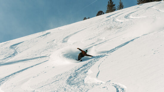 A snowboarder rips through an open bowl of fresh powder at Snowbasin.