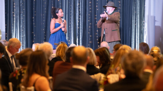 Tom Kelly, pictured here volunteering in October at Deer Valley Resort's Stein Eriksen Lodge on stage as the Master of Ceremonies of Jans Winter Welcome introducing a young figureskater.