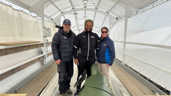 Army veteran David Snypes Junior (center) poses with the specially-designed sled at the Mt. Van Hoevenberg Olympic Bobsled Run.