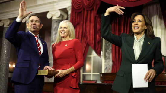 U.S. Vice President Kamala Harris (R) and Sen. John Curtis (R-UT) (L) gesture as his wife Sue Snarr Curtis (2nd L) looks on during a ceremonial swearing-in at the U.S. Capitol on January 3, 2025 in Washington, DC. The 119th Congress begins its term on Capitol Hill today.