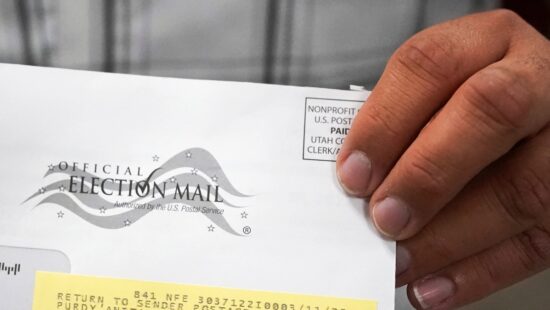 A election worker holds an election envelope during a tour of Utah County's elections equipment and review processes for administering secure elections, April 19, 2022, in Provo, Utah.