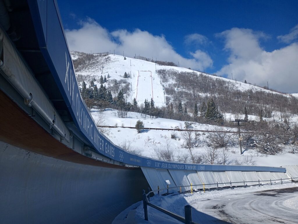 A curve of the sliding track at the Utah Olympic Park with ski rails behind it.