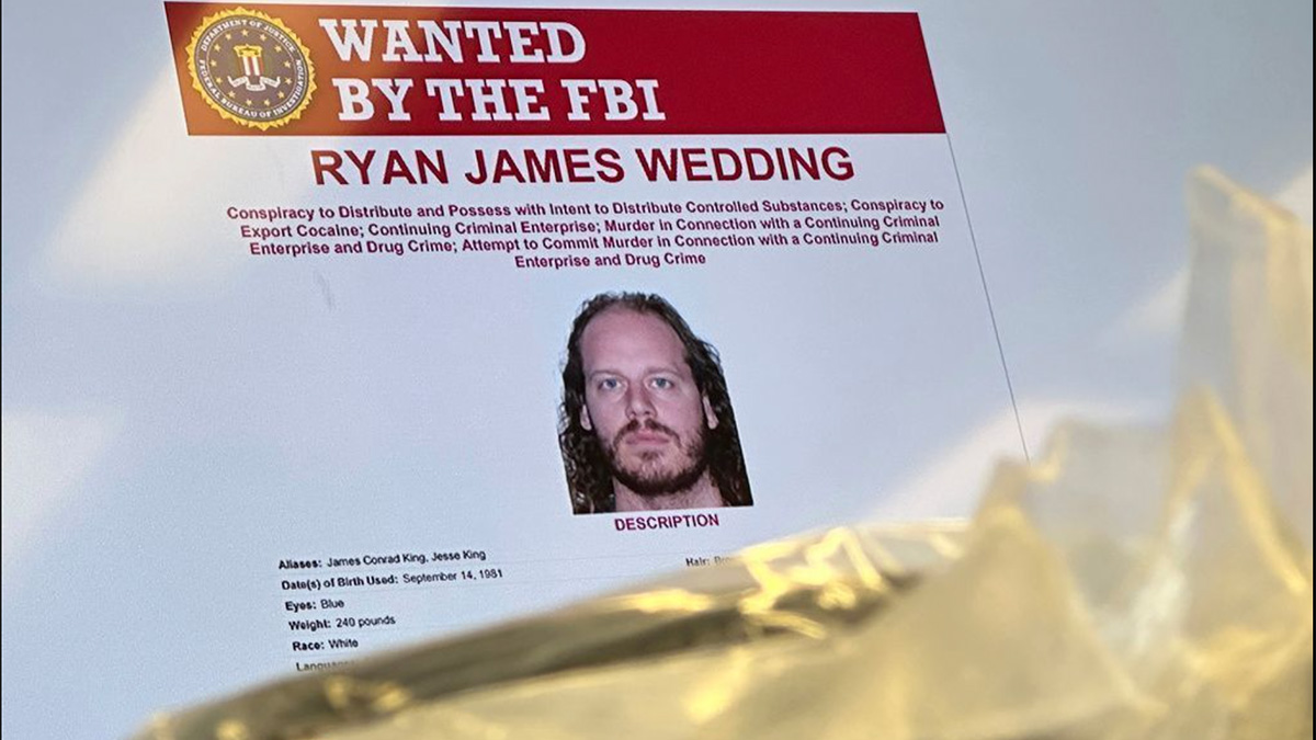 An image of former Canadian Olympic snowboarder Ryan Wedding, 43, who is a fugitive and charged with allegedly running and participating in a transnational drug trafficking operation, is displayed on a video monitor along with bricks of cocaine, foreground, during a news conference at the FBI offices in Los Angeles, Thursday, Oct. 17, 2024.