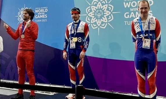 Hyrum Palmer, right, stands on the third-place podium in Italy for snowshoeing at the Winter Games.